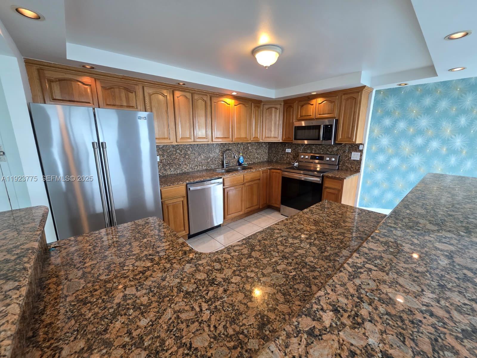7135 Collins Avenue, Unit 725 Miami Beach, FL 33141 - Photo 7 of 21 a kitchen with stainless steel appliances granite countertop a refrigerator a stove top oven a sink and dishwasher