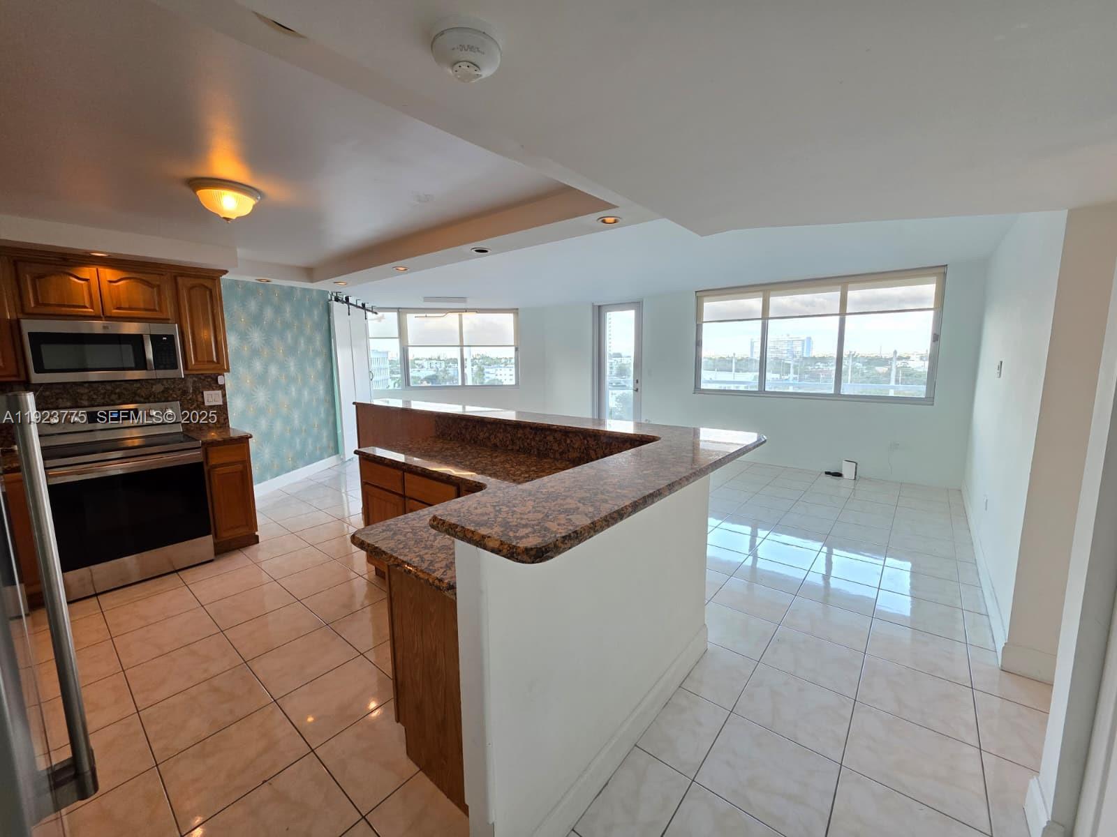 7135 Collins Avenue, Unit 725 Miami Beach, FL 33141 - Photo 9 of 21 a kitchen with stainless steel appliances granite countertop a sink and a stove