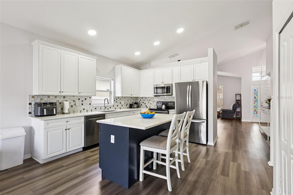 2104 Congress Lane St. Cloud, FL 34769 - Photo 7 of 71 a kitchen with stainless steel appliances kitchen island granite countertop a table chairs sink refrigerator and cabinets