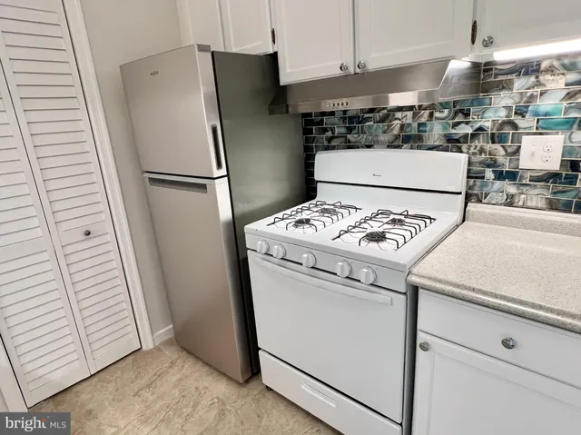 a kitchen with a refrigerator a stove top oven a counter space and a window