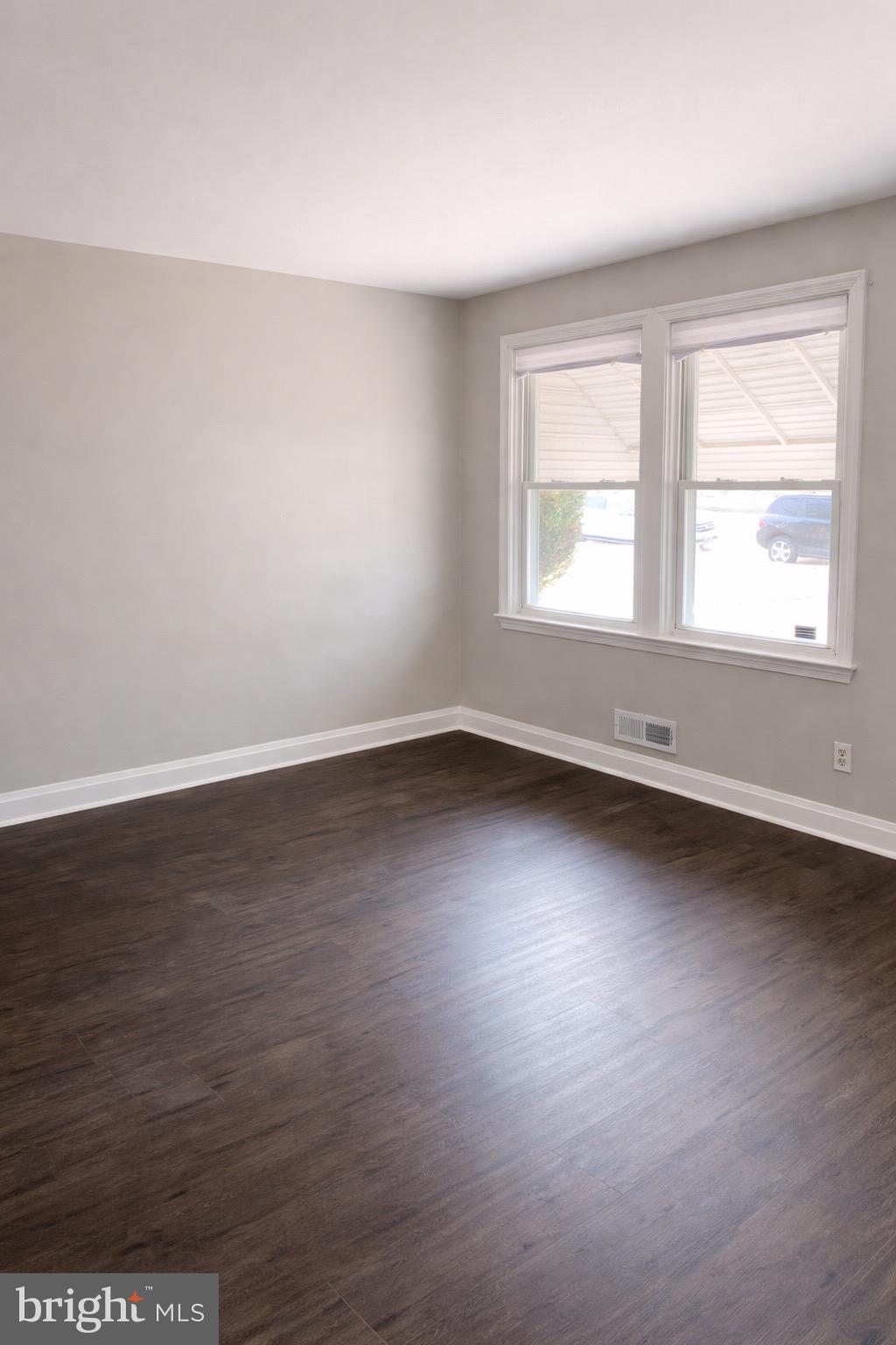 3582 Dudley Avenue Baltimore, MD 21213 - Photo 4 of 12 an empty room with wooden floor and windows