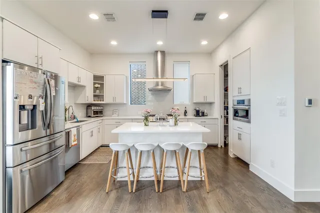 a kitchen with stainless steel appliances white cabinets and wooden floor