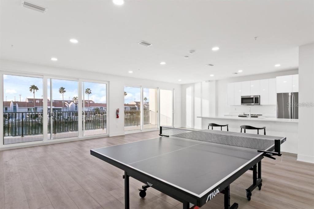 400 150th Avenue, Unit 504 Madeira Beach, FL 33708 - Photo 55 of 60 a dining hall with stainless steel appliances a dining table wooden floor and a large window