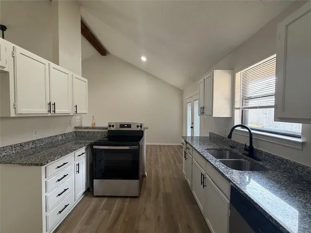 a kitchen with granite countertop a sink stove and cabinets