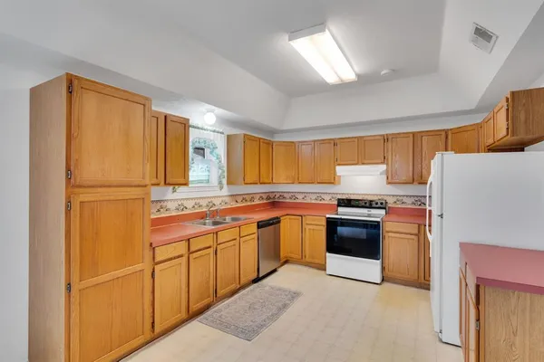 a kitchen with stainless steel appliances granite countertop a refrigerator a sink dishwasher a stove with white cabinets and wooden floor