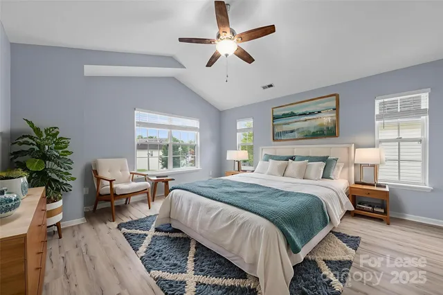 a bedroom with a bed wooden floor and a large window