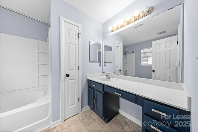 a bathroom with a tub a double vanity sink and mirror