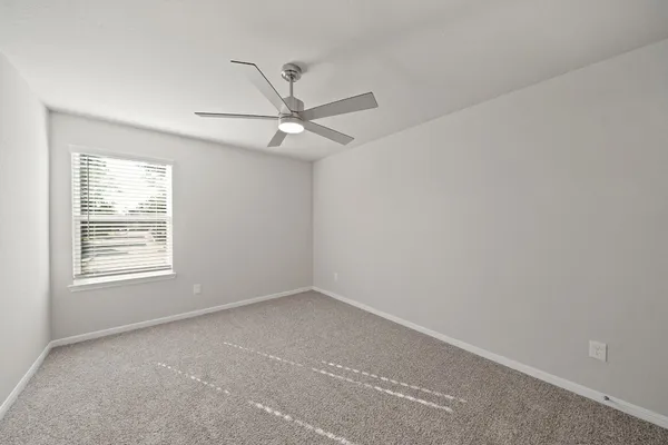 an empty room with a window and a fan