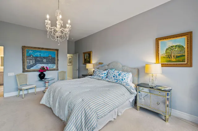 a spacious bedroom with a bed a chandelier and a dresser