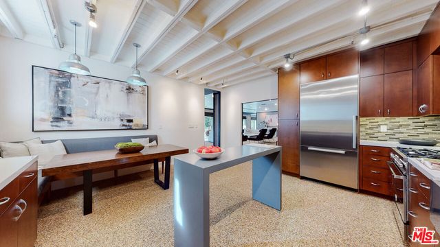 a kitchen with stainless steel appliances kitchen island granite countertop a table chairs in it and wooden floors