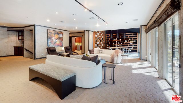 a living room with furniture a table and kitchen view