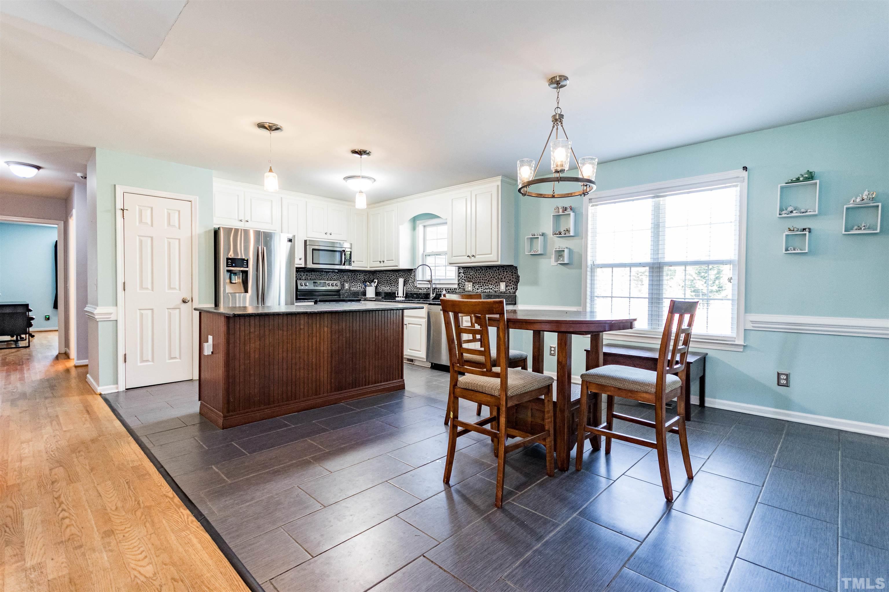 519 Axum Road Willow Spring, NC 27592 - Photo 11 of 30 a open dining room with stainless steel appliances kitchen island granite countertop a table chairs and a refrigerator