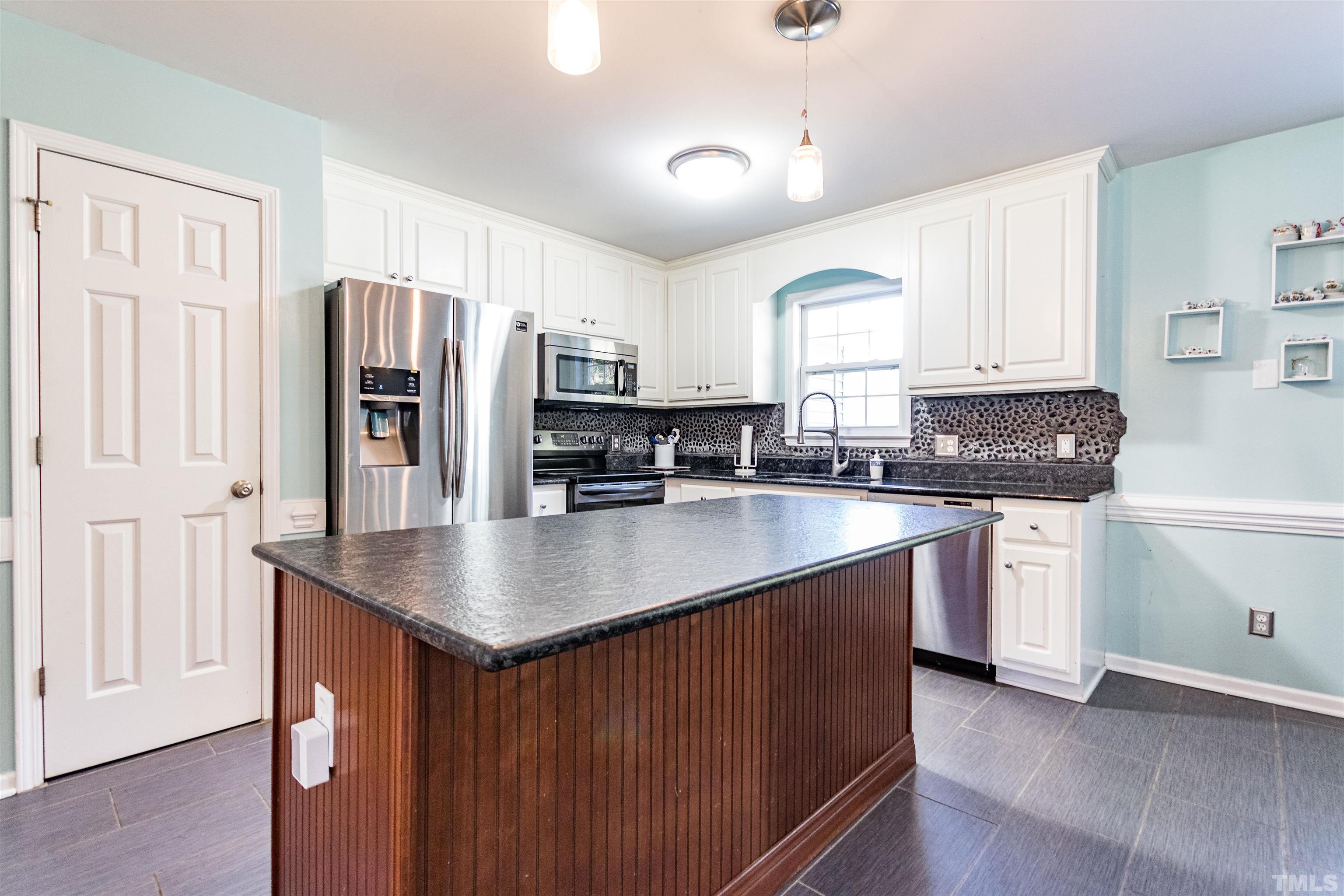 519 Axum Road Willow Spring, NC 27592 - Photo 14 of 30 a kitchen with stainless steel appliances granite countertop a sink a stove a refrigerator a center island with wooden floor