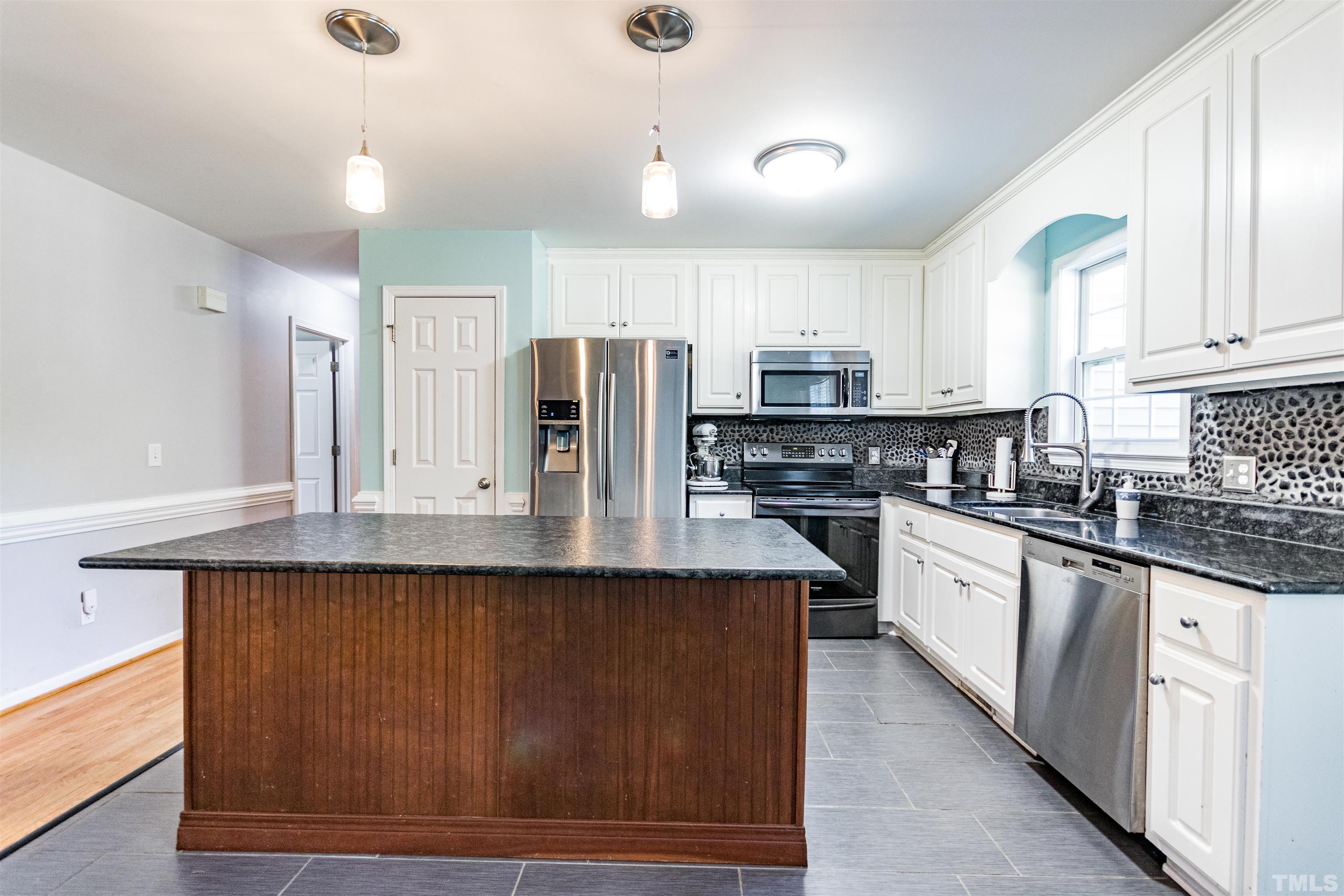 519 Axum Road Willow Spring, NC 27592 - Photo 15 of 30 a kitchen with stainless steel appliances granite countertop a stove a sink dishwasher a refrigerator and white cabinets with wooden floor