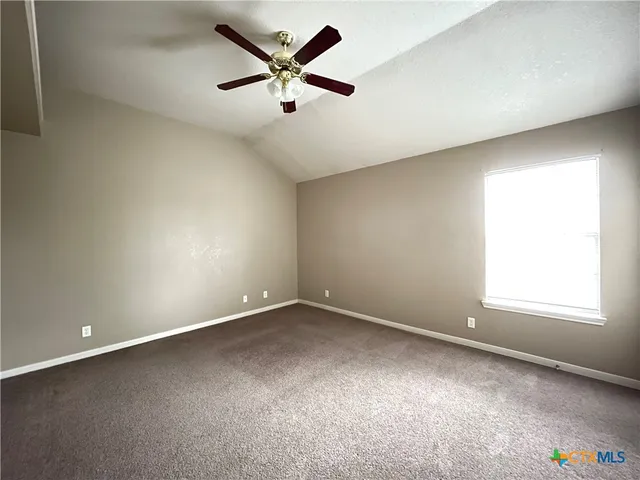 an empty room with a window and a ceiling fan