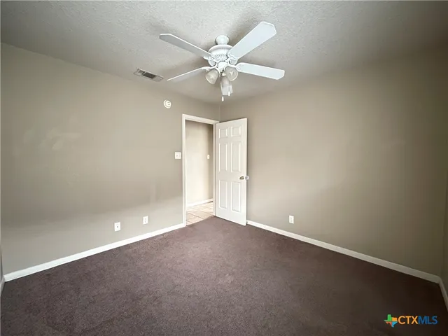 an empty room with a ceiling fan and a window