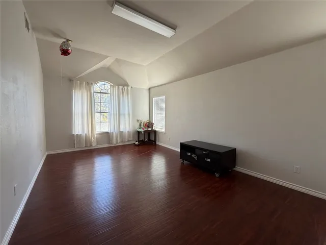 an empty room with wooden floor and window