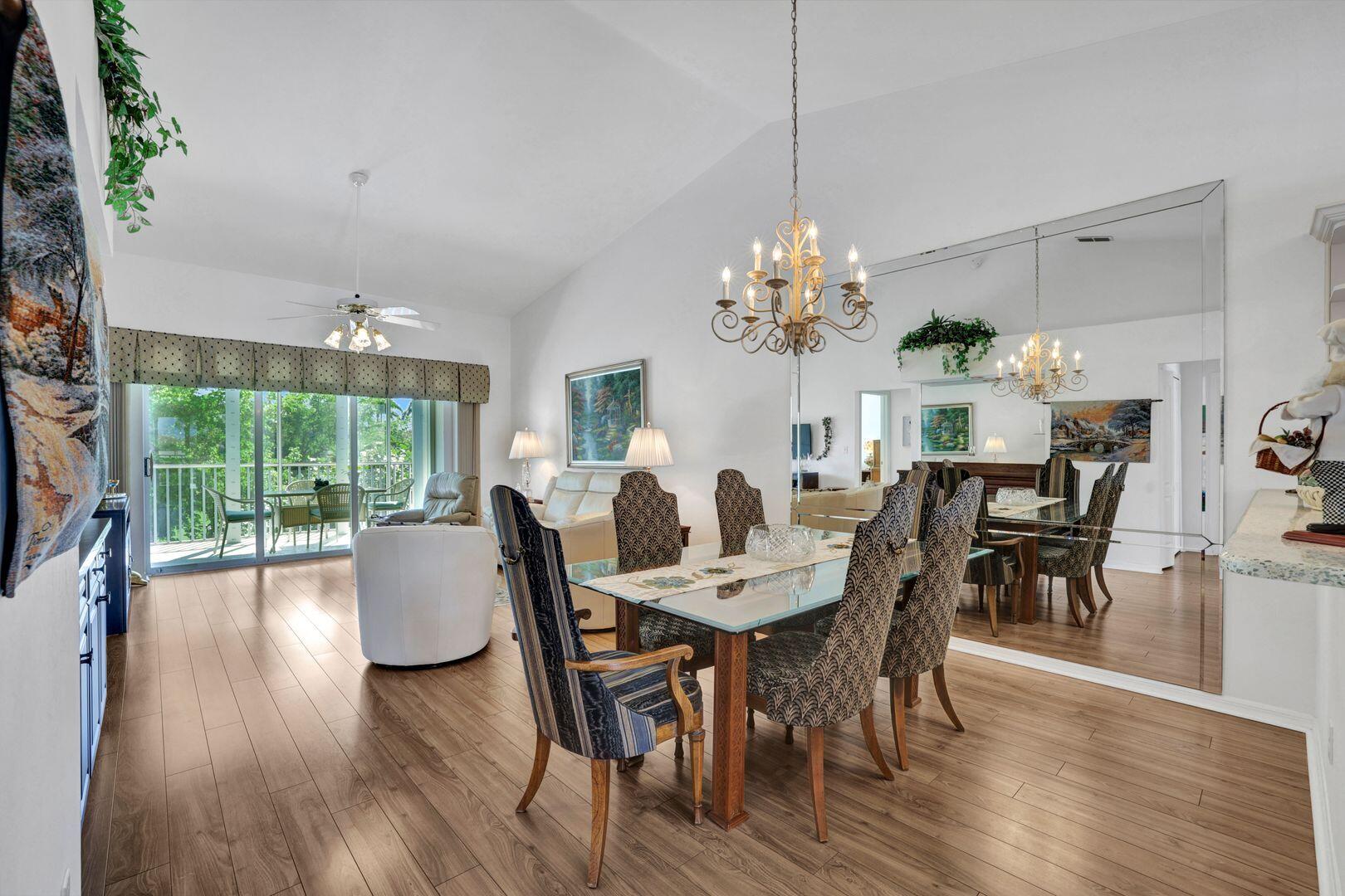 1006 Mainsail Drive, Unit 224 Naples, FL 34114 - Photo 11 of 30 a dining room with furniture a chandelier and wooden floor