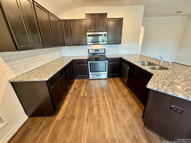 a kitchen with granite countertop a sink stove and refrigerator