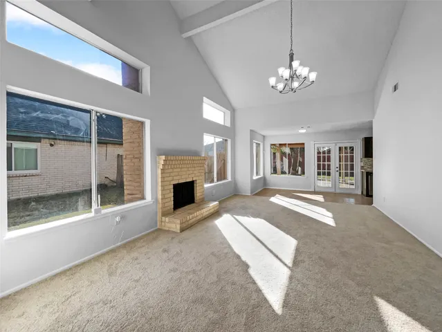 a view of an empty room with a fireplace and chandelier