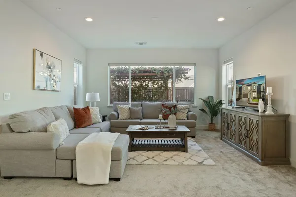a living room with furniture and a dining table with kitchen view