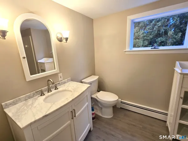 a bathroom with a granite countertop sink mirror vanity and toilet