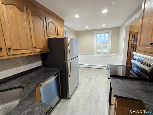 a kitchen with granite countertop a refrigerator and a stove top oven