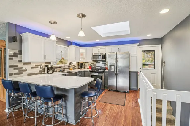 a kitchen with stainless steel appliances kitchen island granite countertop a dining table chairs and white cabinets