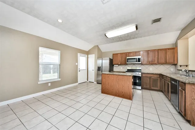 a large kitchen with stainless steel appliances kitchen island granite countertop a sink and cabinets