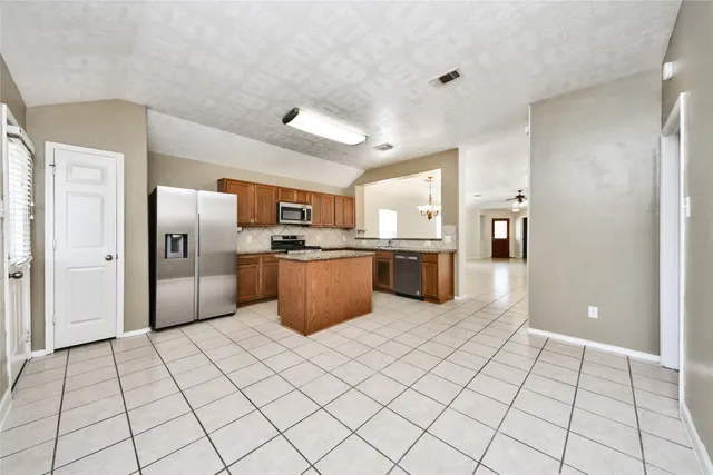 a large white kitchen with a sink and dishwasher a refrigerator with wooden cabinets