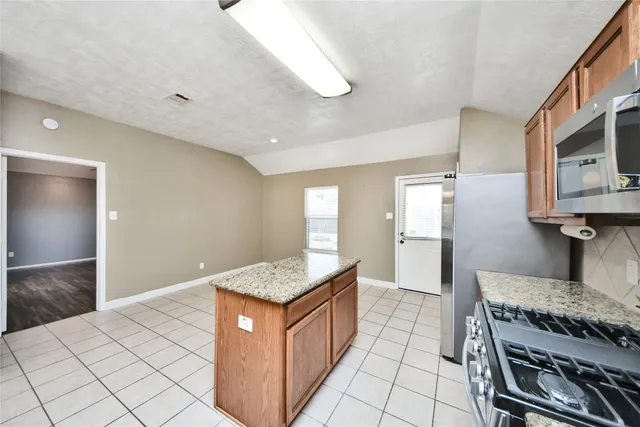 a kitchen with stainless steel appliances granite countertop a stove a sink and a microwave