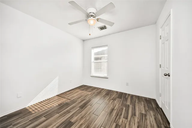 a view of a room with wooden floor and a ceiling fan