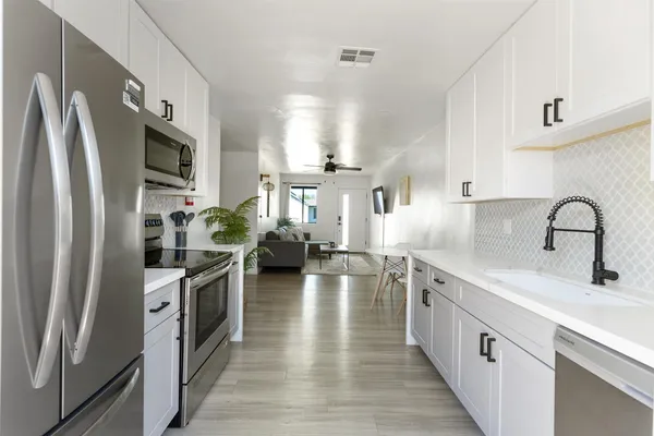 a kitchen with stainless steel appliances a sink dishwasher a refrigerator and a stove with wooden floor