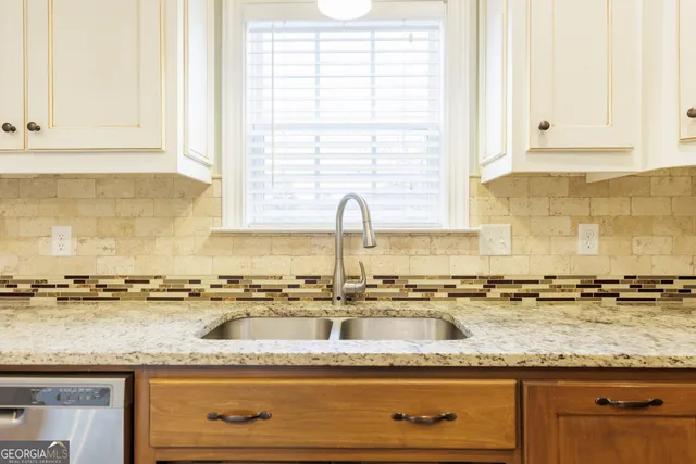 a kitchen with granite countertop white cabinets and a sink