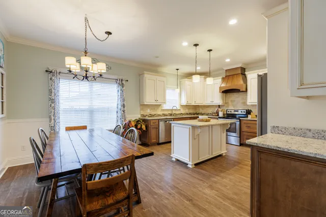 a kitchen with a dining table chairs stainless steel appliances and cabinets