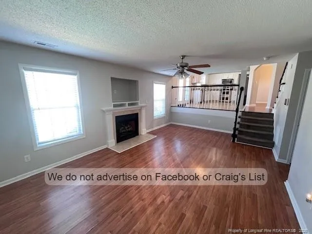 an empty room with wooden floor fireplace and windows