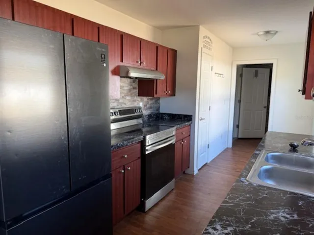 a kitchen with stainless steel appliances granite countertop a refrigerator stove and sink