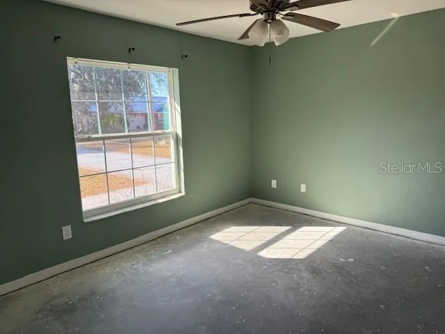 an empty room with a window and a fan