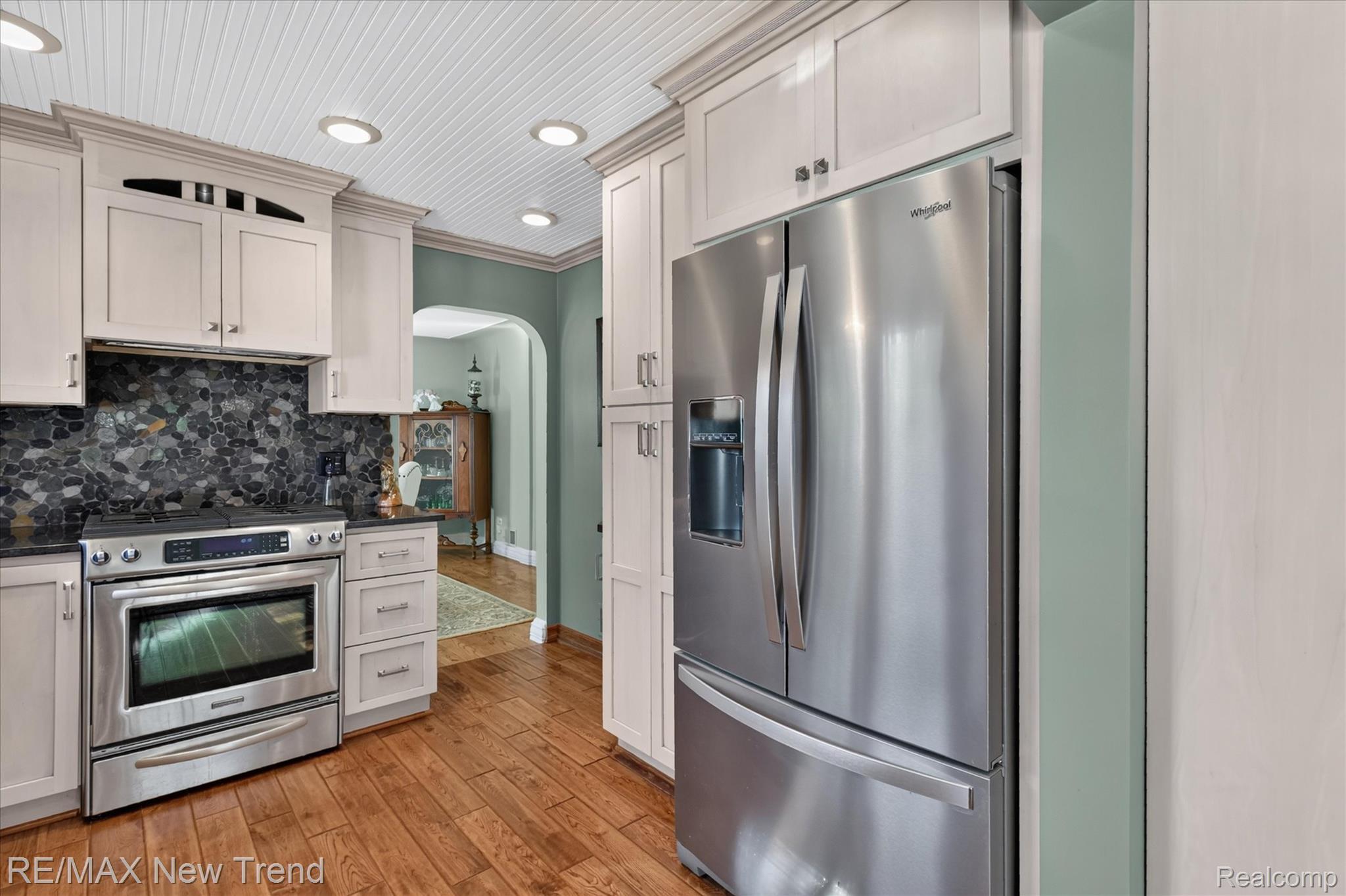 2529 South Commerce Road Walled Lake, MI 48390 - Photo 21 of 66 Wood-finish flooring, stainless steel appliances, beadboard ceiling with recessed lighting, custom cabinetry, and a stone mosaic backsplash