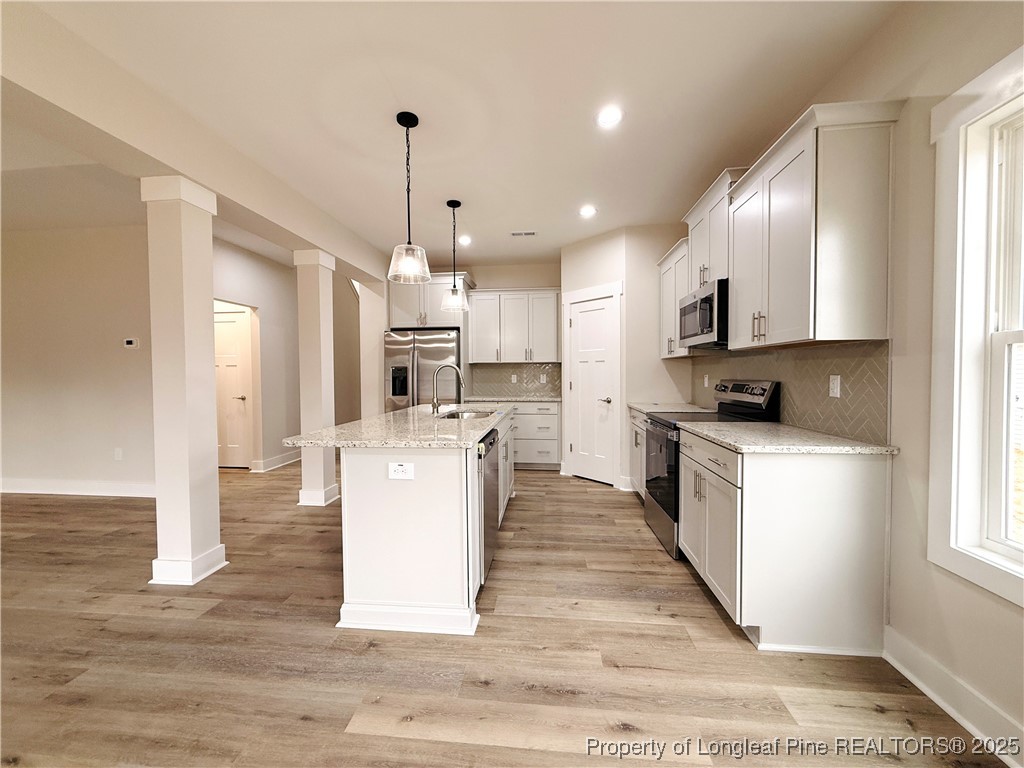 279 Elijah Way Vass, NC 28394 - Photo 16 of 36 a living room with stainless steel appliances kitchen island granite countertop a refrigerator a stove top oven and a sink with granite countertops