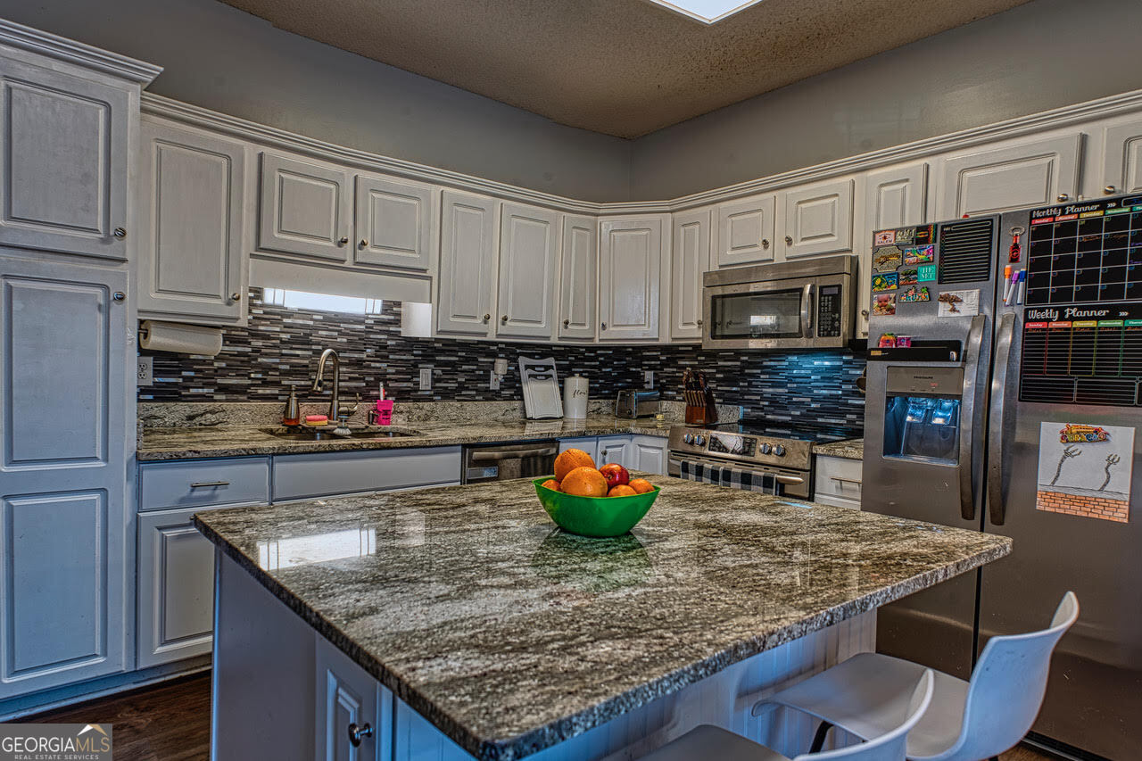 221 Pendleton Court Macon, GA 31216 - Photo 7 of 16 a kitchen with stainless steel appliances granite countertop a table chairs sink and cabinets