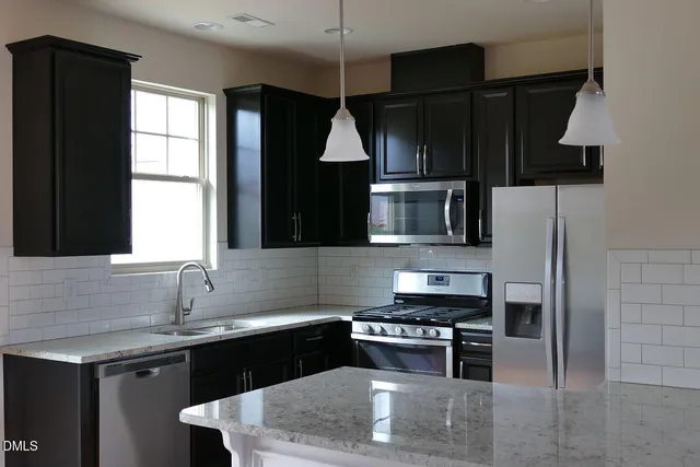 a kitchen with kitchen island granite countertop a sink a stove and refrigerator