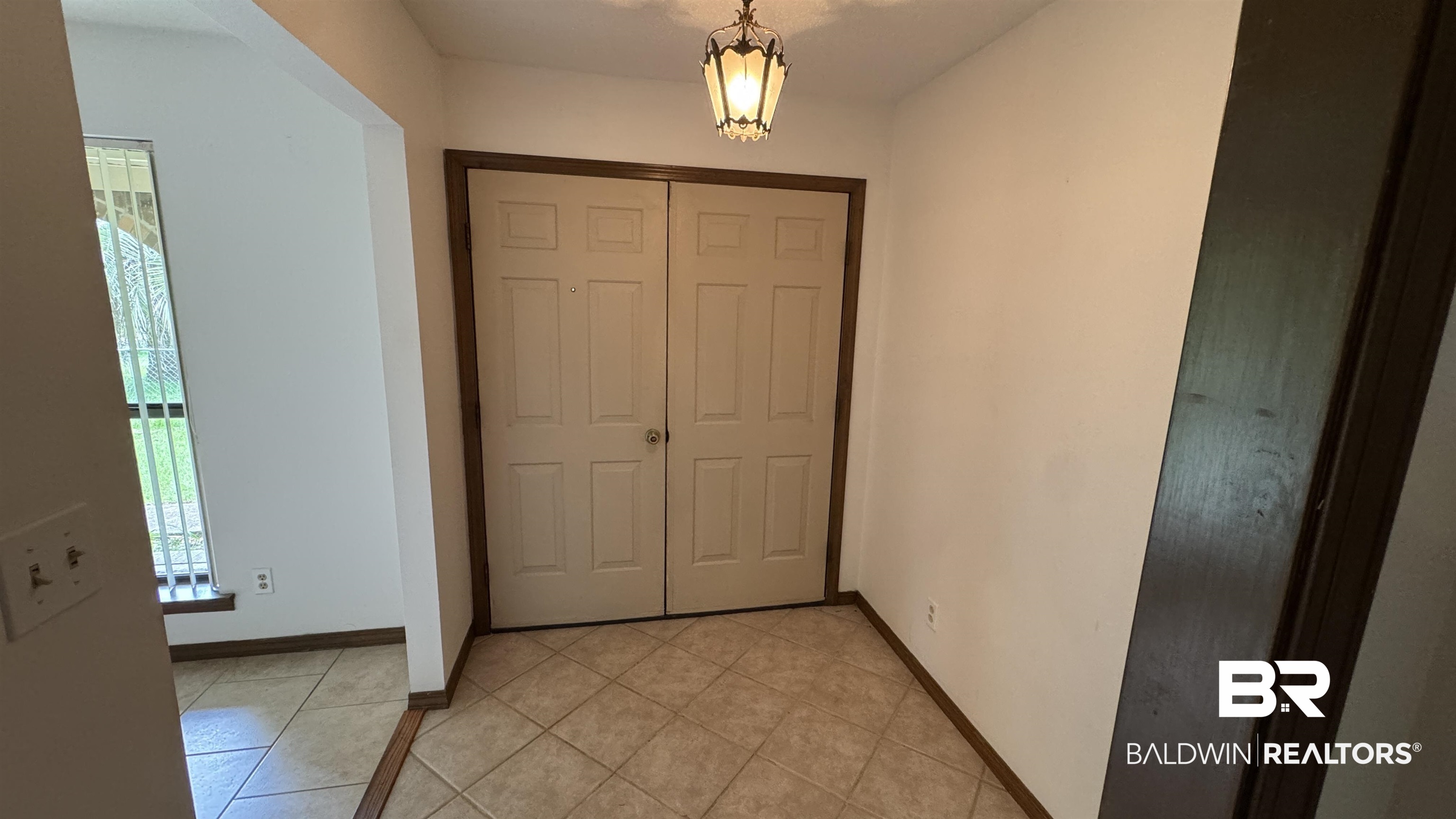 33370 Highway 98 Lillian, AL 36549 - Photo 18 of 58 Foyer featuring light-toned tile flooring, a geometric flush-mount light fixture, and a pair of bi-fold doors with dark wood trim