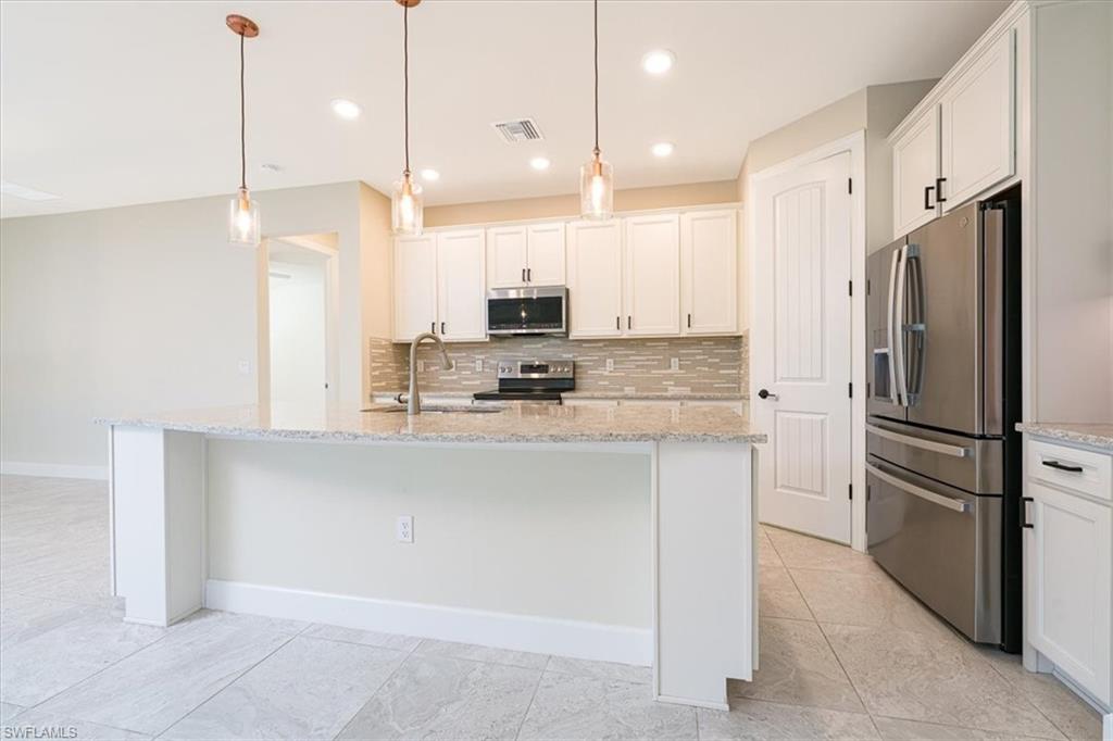 1996 Parson Street Naples, FL 34120 - Photo 19 of 50 Kitchen featuring tasteful backsplash, white cabinets, appliances with stainless steel finishes, light stone counters, and recessed lighting