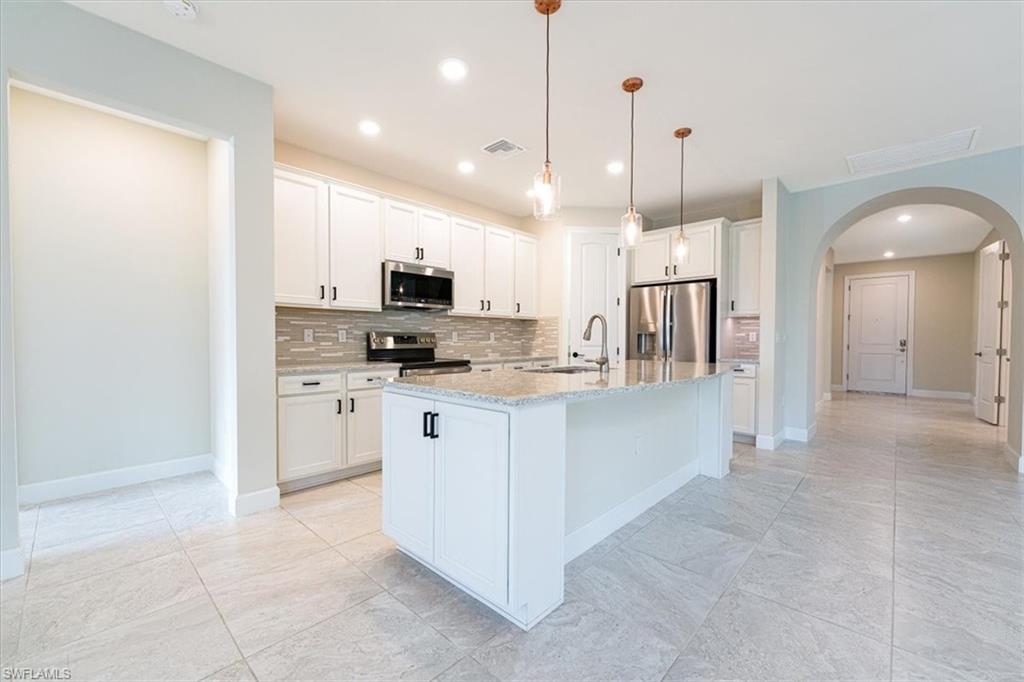 1996 Parson Street Naples, FL 34120 - Photo 20 of 50 Kitchen featuring tasteful backsplash, white cabinets, appliances with stainless steel finishes, arched walkways, and decorative light fixtures