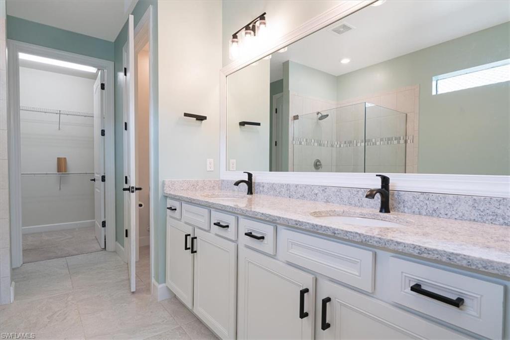 1996 Parson Street Naples, FL 34120 - Photo 31 of 50 Full bathroom with double vanity, a spacious closet, a shower stall, and light tile patterned floors