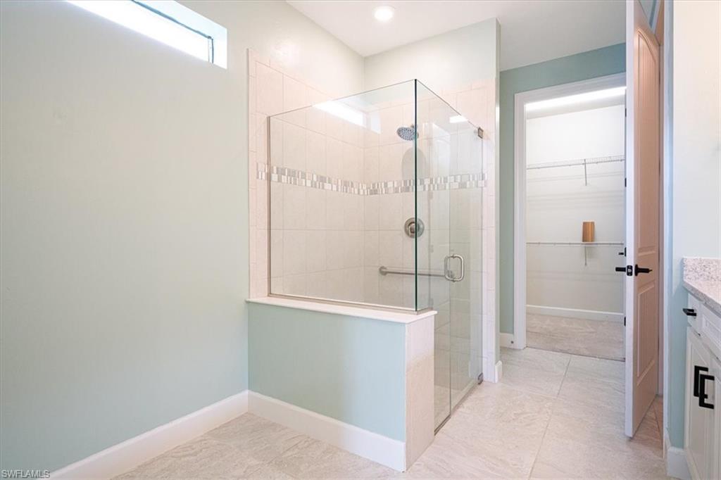 1996 Parson Street Naples, FL 34120 - Photo 32 of 50 Full bathroom featuring a walk in closet, vanity, a shower stall, and light tile patterned floors