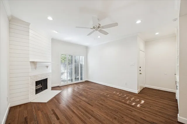 an empty room with wooden floor fireplace and windows
