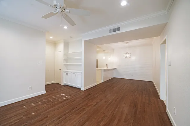 an empty room with wooden floor chandelier fan and windows