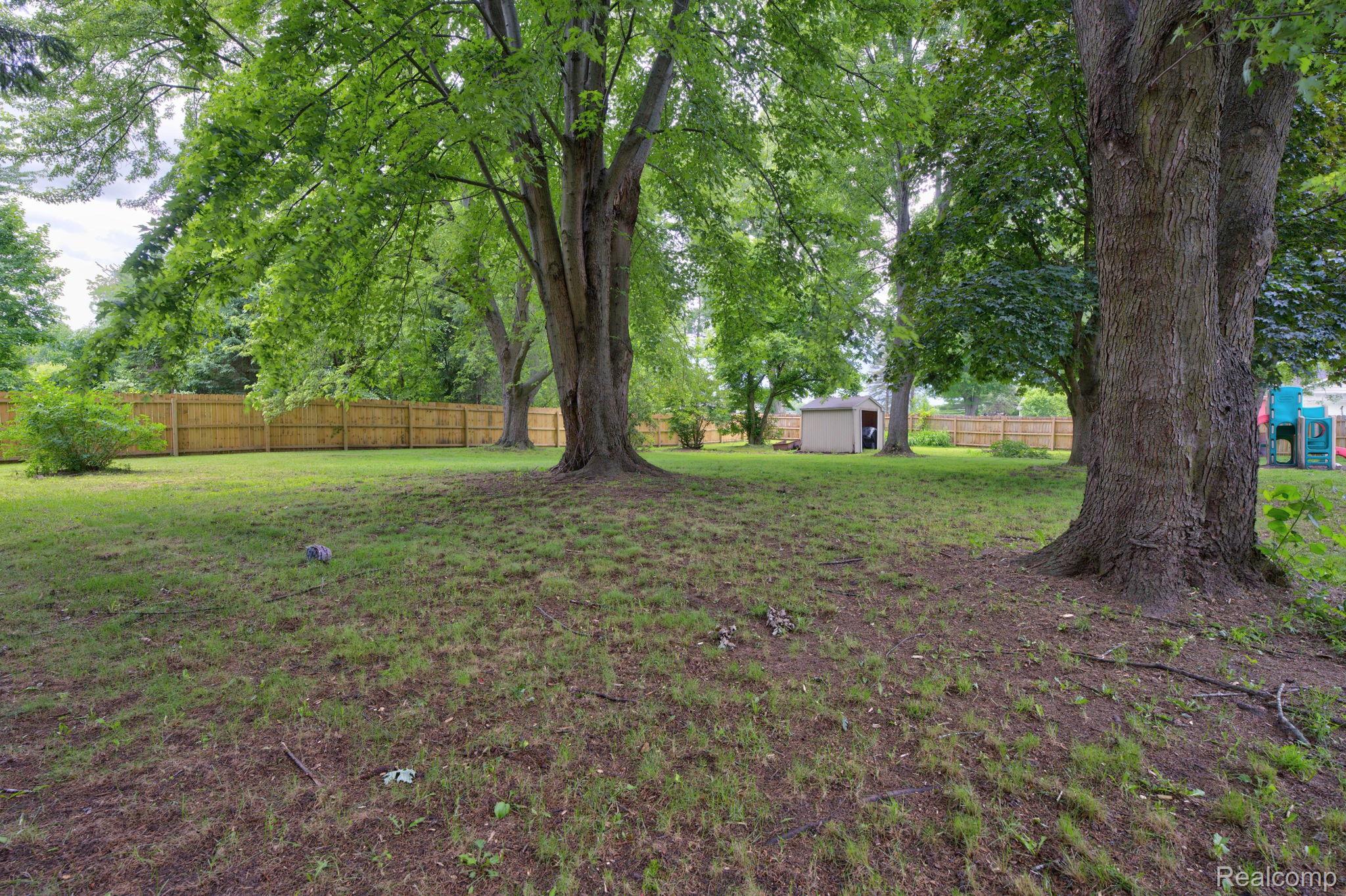 5330 Sheridan Road Saginaw, MI 48601 - Photo 47 of 50 Expansive backyard featuring mature trees, a wood privacy fence, and a storage shed
